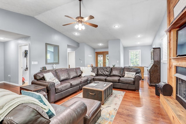 living area featuring a ceiling fan, a fireplace, baseboards, lofted ceiling, and hardwood / wood-style floors