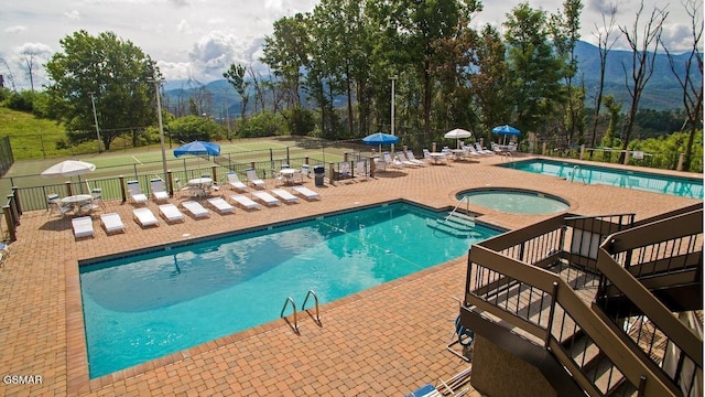 view of pool featuring a hot tub, a patio, and a mountain view