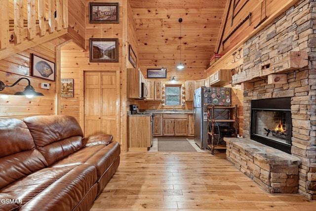 living room with high vaulted ceiling, wooden walls, a fireplace, light hardwood / wood-style floors, and wood ceiling