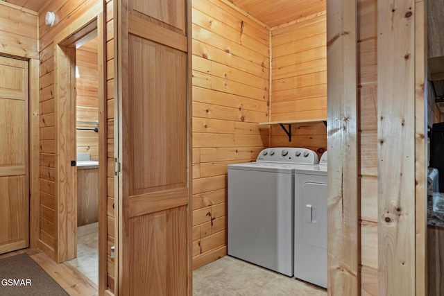 laundry area featuring wooden walls, washer and clothes dryer, light tile patterned floors, and wooden ceiling