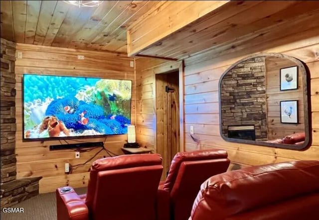 carpeted home theater room featuring wood ceiling, a fireplace, and wooden walls