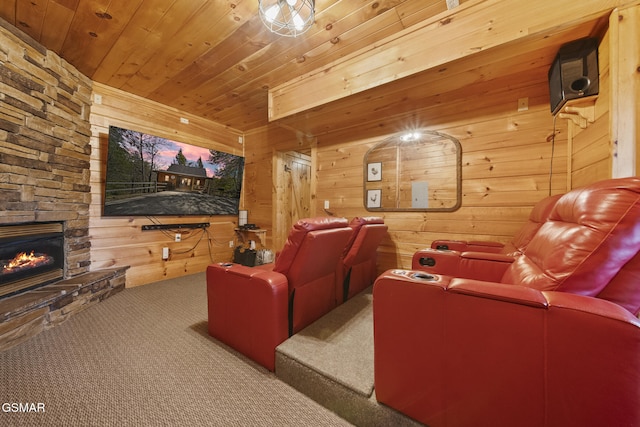 home theater featuring an outdoor stone fireplace, carpet, wood ceiling, and wooden walls