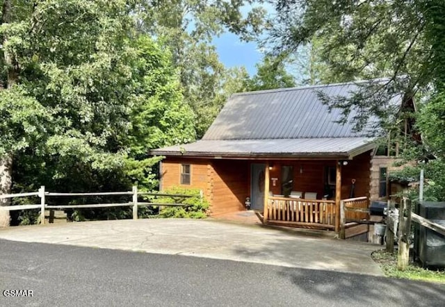 view of front of home with metal roof, covered porch, and fence