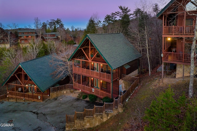 back house at dusk featuring a balcony