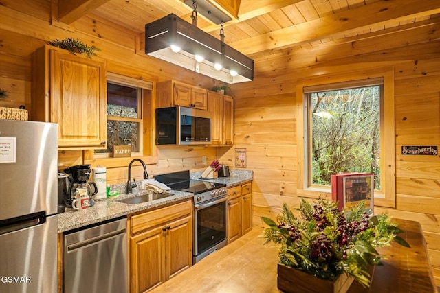 kitchen with wood walls, beam ceiling, sink, and stainless steel appliances