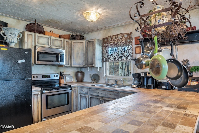 kitchen featuring crown molding, stainless steel appliances, tile counters, and sink