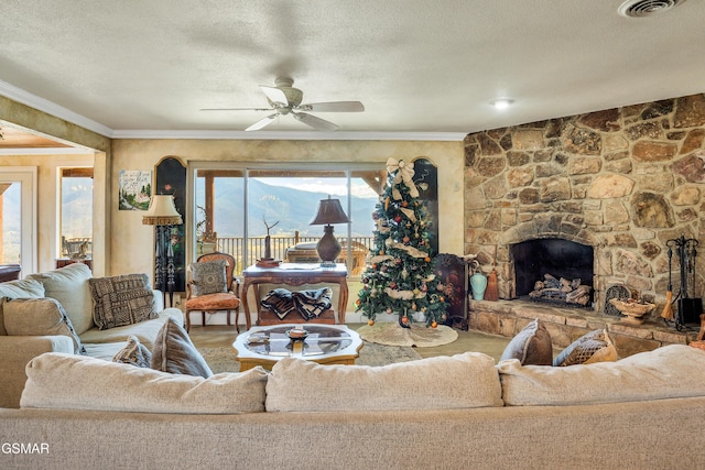 living room with a textured ceiling, ornamental molding, hardwood / wood-style flooring, ceiling fan, and a fireplace