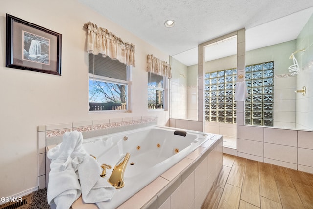 bathroom featuring a relaxing tiled tub and a textured ceiling