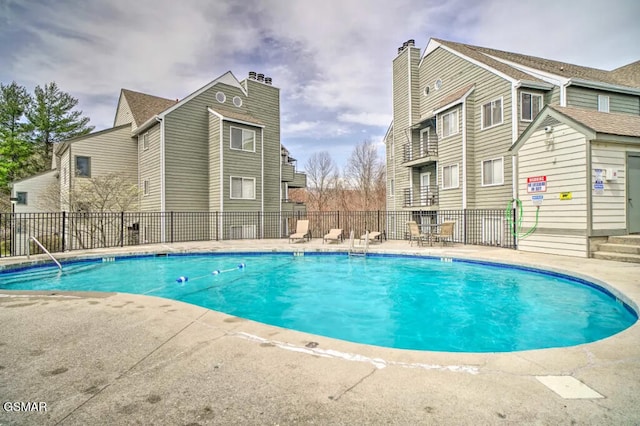 community pool with fence and a patio