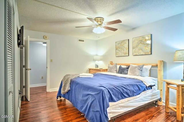 bedroom featuring a textured ceiling, dark wood finished floors, visible vents, and baseboards