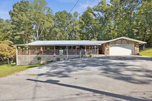 view of front of home with metal roof, aphalt driveway, covered porch, a garage, and stone siding