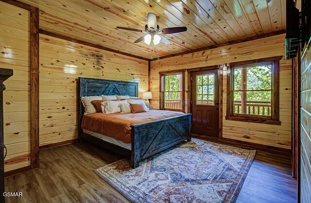 bedroom with dark hardwood / wood-style flooring, wooden walls, ceiling fan, and wooden ceiling