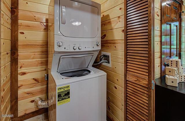 washroom with wood walls and stacked washer / drying machine