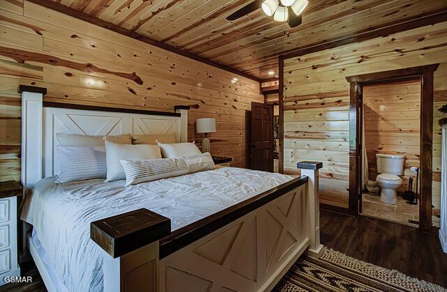 bedroom featuring ceiling fan, dark hardwood / wood-style floors, wooden ceiling, and wooden walls