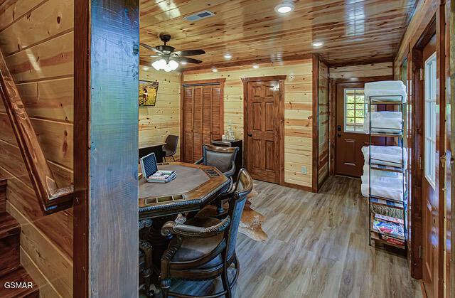 office area featuring ceiling fan, wood walls, wood-type flooring, and wooden ceiling