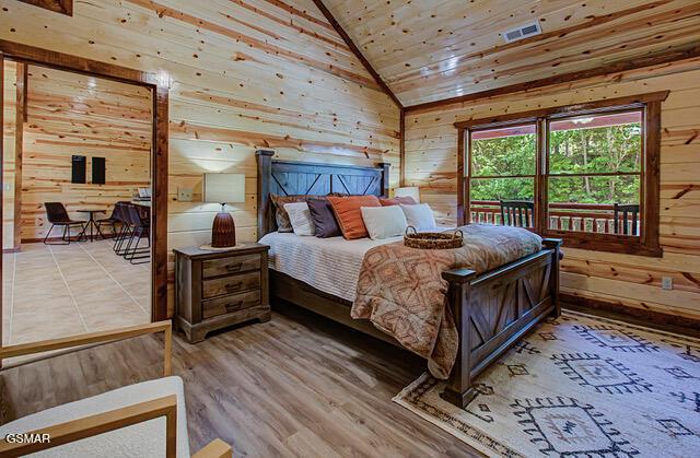 bedroom featuring wood-type flooring, lofted ceiling, wooden walls, and wooden ceiling