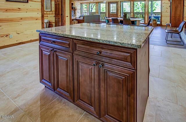 kitchen featuring a center island, light stone counters, and wood walls