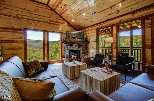 living room with a fireplace, high vaulted ceiling, wooden ceiling, and wood walls