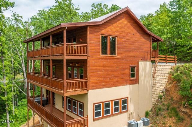 view of side of property featuring cooling unit and a balcony