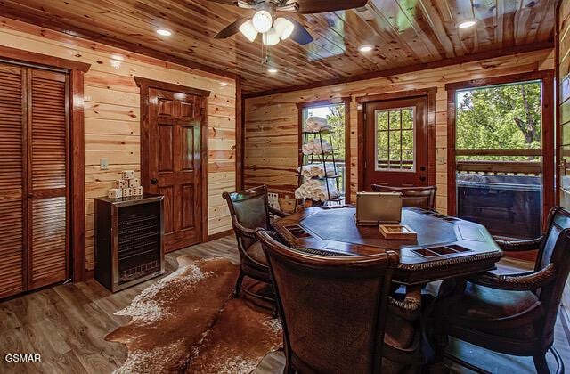 dining room with hardwood / wood-style flooring, ceiling fan, wood ceiling, and wooden walls