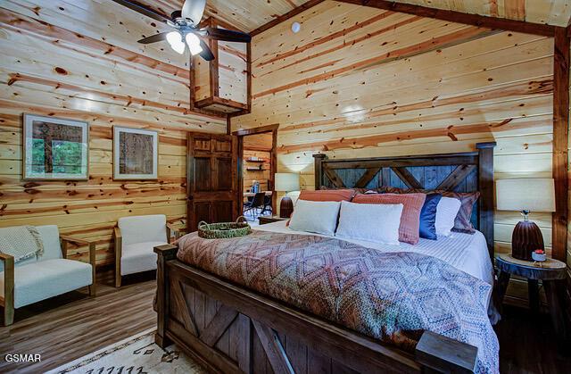 bedroom with hardwood / wood-style flooring, ceiling fan, wooden ceiling, and wooden walls