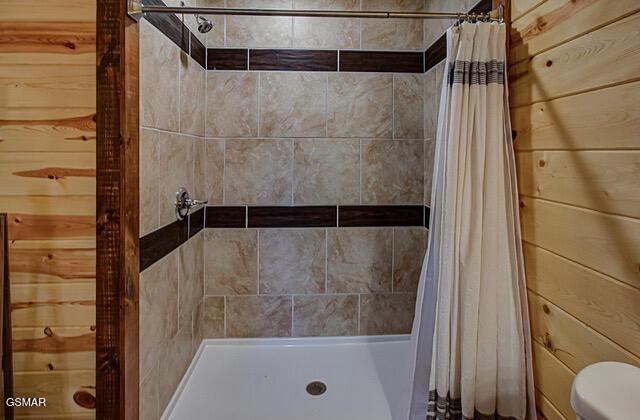 bathroom featuring curtained shower, wood walls, and toilet