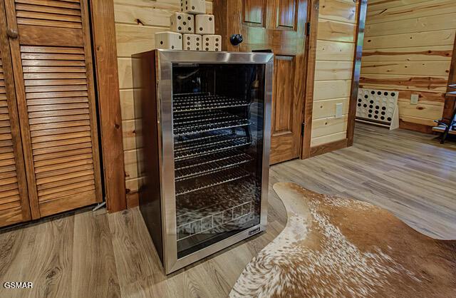 details with wine cooler, wood walls, and hardwood / wood-style flooring