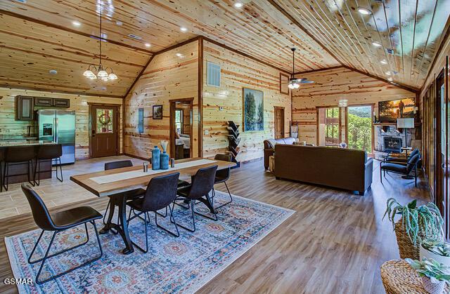 dining room featuring wooden walls, wood ceiling, and wood-type flooring