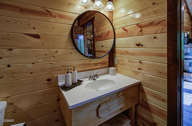 bathroom featuring vanity, toilet, and wood walls