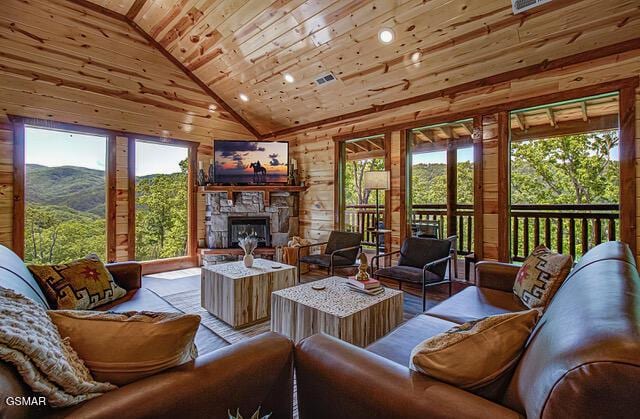 living room with a healthy amount of sunlight, a stone fireplace, wood walls, and wooden ceiling