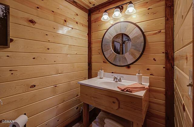 bathroom featuring sink, wooden ceiling, and wood walls