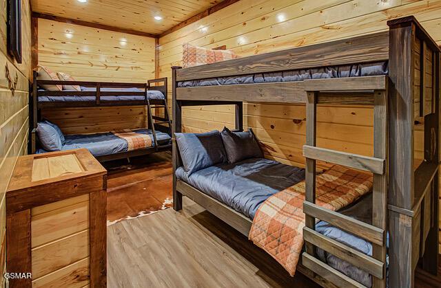 bedroom featuring wooden walls, hardwood / wood-style flooring, and wooden ceiling