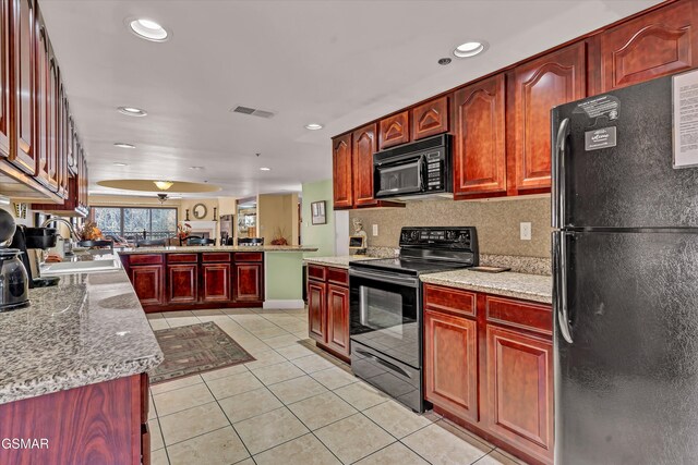 kitchen featuring sink, light stone counters, backsplash, light tile patterned flooring, and black appliances