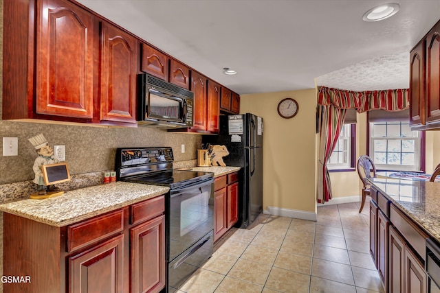 kitchen featuring tasteful backsplash, light stone countertops, light tile patterned flooring, and black appliances