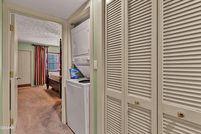 laundry area featuring a textured ceiling, light colored carpet, and stacked washer and clothes dryer