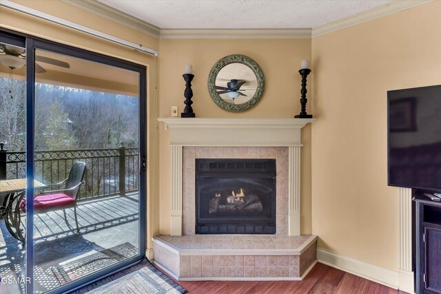 living room with ceiling fan, a textured ceiling, hardwood / wood-style flooring, a fireplace, and ornamental molding