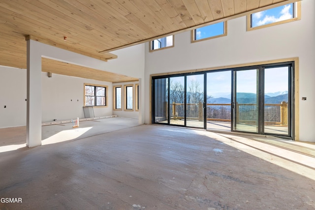 unfurnished living room with wooden ceiling, a high ceiling, and a mountain view