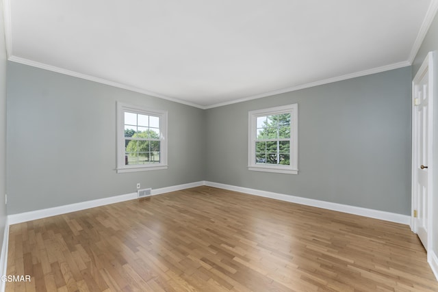 empty room with plenty of natural light, light hardwood / wood-style flooring, and ornamental molding