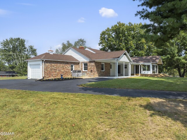 ranch-style house featuring a front lawn, covered porch, and a garage