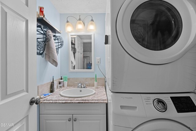 bathroom featuring vanity, stacked washing maching and dryer, and a textured ceiling