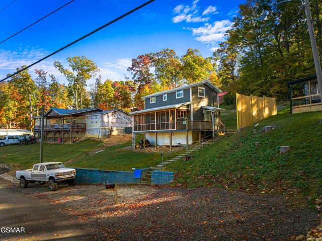 view of front of property featuring a front lawn, a wooden deck, and a sunroom