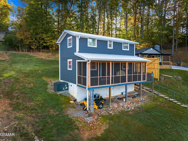 back of property with a yard, central AC unit, and a sunroom