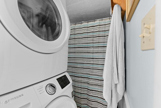 clothes washing area with stacked washer and dryer and a textured ceiling