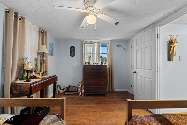 bedroom with hardwood / wood-style flooring, ceiling fan, and a textured ceiling