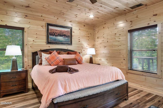 bedroom featuring wooden ceiling, wooden walls, ceiling fan, light wood-type flooring, and multiple windows