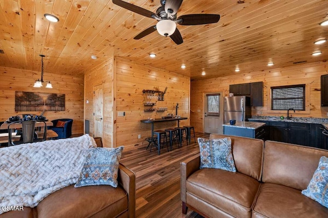 living room featuring ceiling fan, sink, dark hardwood / wood-style flooring, wooden walls, and wood ceiling