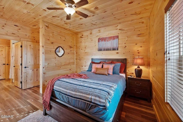 bedroom featuring ceiling fan, wood-type flooring, wooden ceiling, and wooden walls