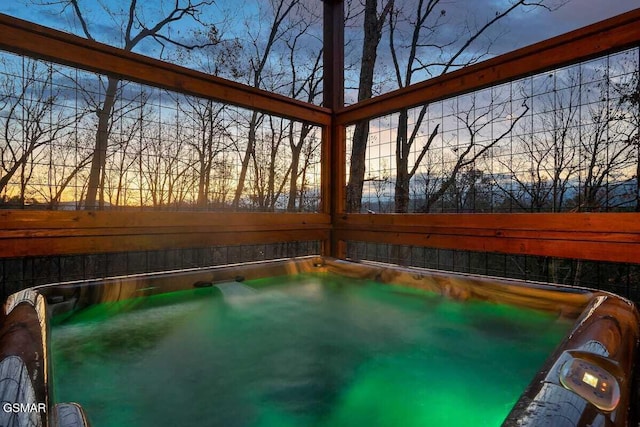 pool at dusk featuring a hot tub