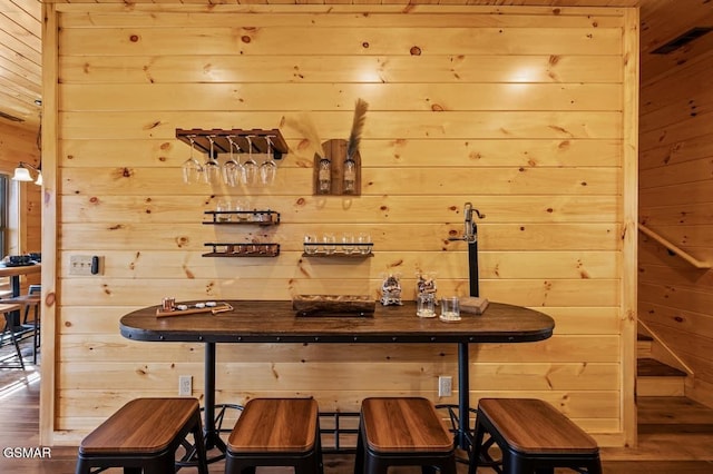 bar featuring wood-type flooring and wooden walls