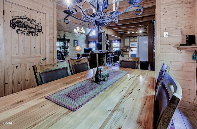 3050 Headrick Dr, Sevierville, TN 37862 - dining space featuring an inviting chandelier, wood walls, beam ceiling, and hardwood / wood-style floors